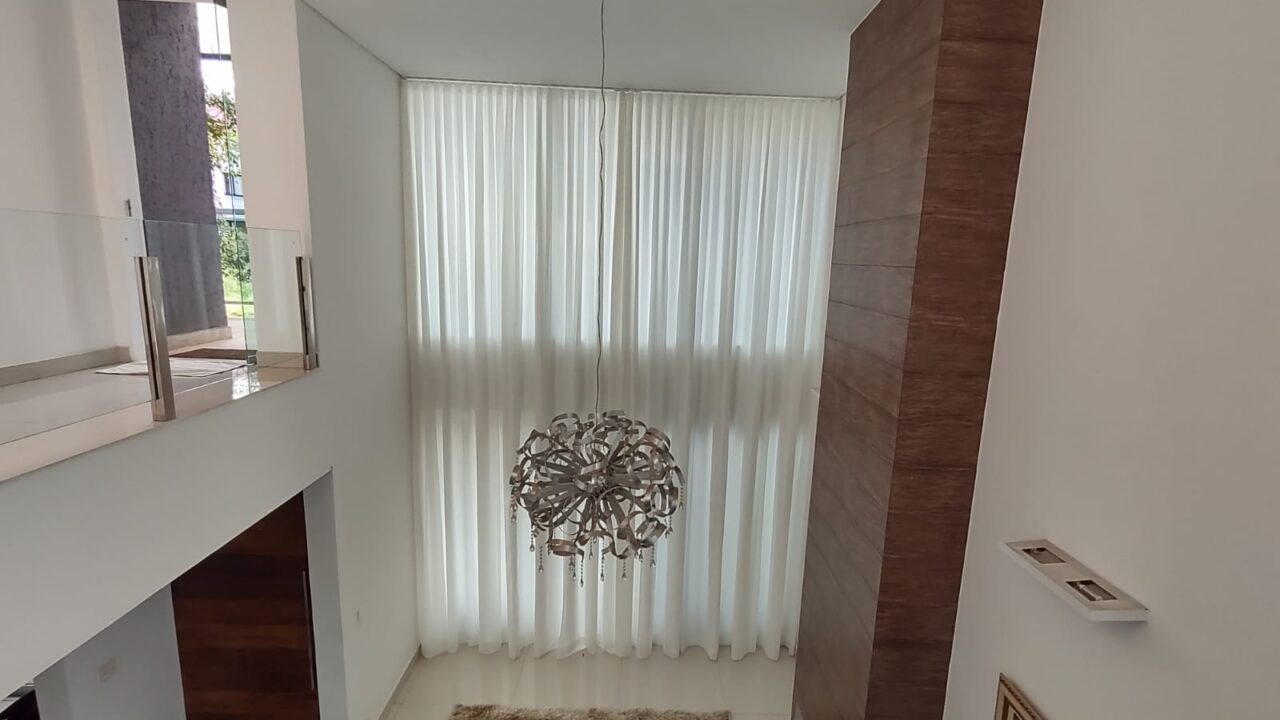 Cortina translúcida em sala com pé-direito duplo: a automação permite controlar a entrada de luz com um comando.