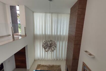 Cortina translúcida em sala com pé-direito duplo: a automação permite controlar a entrada de luz com um comando.